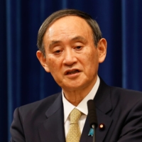 Prime Minister Yoshihide Suga holds a news conference Wednesday night. Japan’s mildly worded rebuke stood in contrast to the forceful language used by leaders around the globe against U.S. President Donald Trump. | POOL / VIA AFP-JIJI