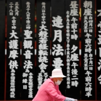 An elderly woman walks past a Buddhist temple in Tokyo\'s Asakusa neighborhood amid the COVID-19 outbreak in July. | REUTERS