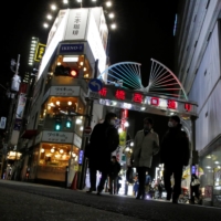 People leave a street in a commercial district before 8 p.m., the time the government is asking restaurants and bars to close by, in Tokyo on Friday. | REUTERS