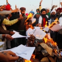 Farmers burn copies of a law on agriculture that is target of mass protests at the Delhi-Uttar Pradesh border in Ghaziabad, India, on Wednesday.  | REUTERS 