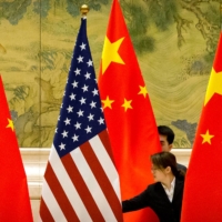 Chinese staffers adjust U.S. and Chinese flags before the opening session of Sino-U.S. trade negotiations in Beijing in February 2019. | POOL / VIA REUTERS