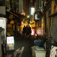 Pedestrians walk through an alley in Tokyo on Jan. 8. | BLOOMBERG