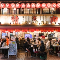 People dine at a restaurant at the Ameya Yokocho market in the Ueno district of Tokyo on Dec. 30. While many restaurants in Tokyo are following the requests in return for subsidies, others are starting to break ranks. | BLOOMBERG