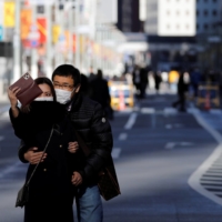 A man and woman take a selfie at Ginza shopping district in Tokyo on Jan. 10. | REUTERS