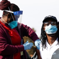 A nurse administers the COVID-19 vaccine in Pasadena, California, on Jan. 12. A relevant fact is that in many countries, disadvantaged racial and ethnic minorities have a lower-than-average life expectancy, raising questions as to who should be vaccinated first. | REUTERS