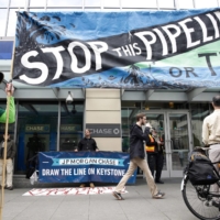 Indigenous leaders and climate activists disrupt business at a Chase Bank branch in Seattle in 2017. U.S. President Joe Biden on Wednesday rescinded the construction permit for the Keystone XL oil pipeline, which would have transported carbon-heavy oil from the Canadian oil sands to the Gulf Coast.  | AFP-JIJI