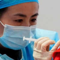 A medical worker prepares to administer a dose of a COVID-19 vaccine in Shanghai on Tuesday.  | REUTERS