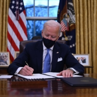 U.S. President Joe Biden signs a series of executive orders in the Oval Office of the White House in Washington, after being sworn in on Wednesday. | AFP-JIJI