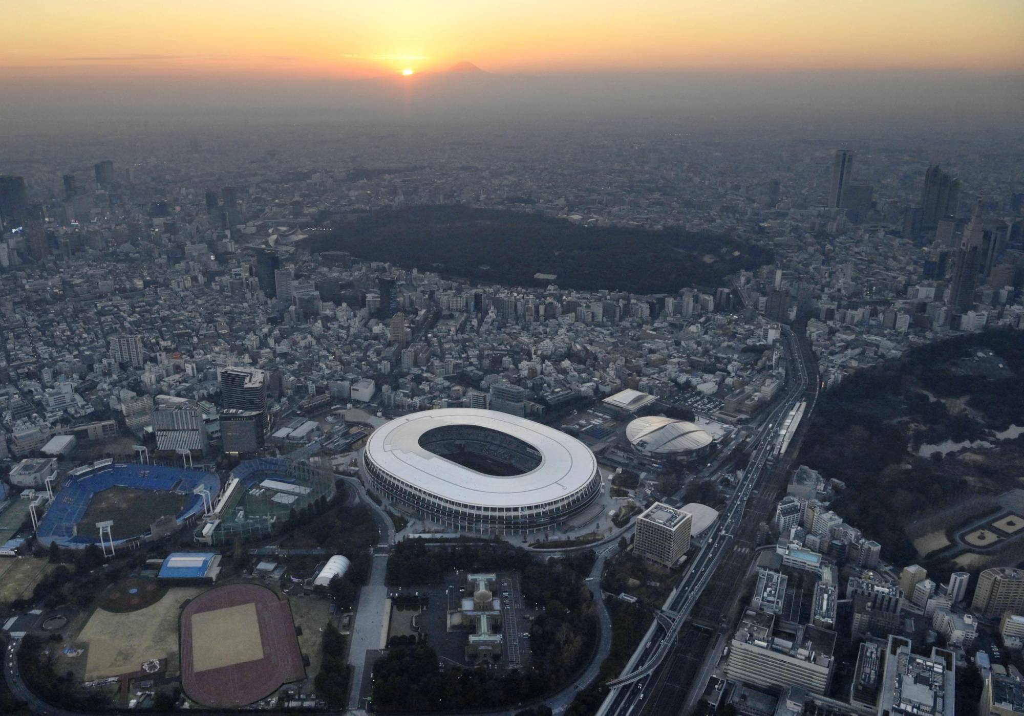 The sun sets on the National Stadium, the main venue for the Tokyo 2020 Olympic and Paralympic Games, on Thursday. Prime Minister Yoshihide Suga has reiterated that the delayed Tokyo Games will not be canceled or postponed. | KYODO