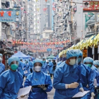 Health workers are seen in protective gear inside a locked-down portion of the Jordan residential area to contain a new coronavirus outbreak in Hong Kong on Saturday. | REUTERS