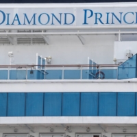 Masked passengers look out from the Diamond Princess cruise ship docked at Yokohama Port in February 2020.  | REUTERS