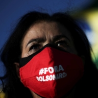 A demonstrator wearing a face mask reading \"Out Bolsonaro\" takes part in a protest against Brazil\'s President Jair Bolsonaro and his handling of the coronavirus outbreak, in Brasilia on Sunday. | REUTERS