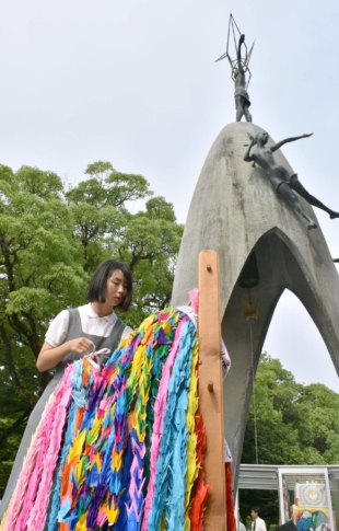 A junior high school student offers paper cranes, a symbol of hope in Japan, at the Children's Peace Monument in the Hiroshima Peace Memorial Park. The monument is modeled after Sadako Sasaki, who died of leukemia 10 years after the 1945 bombing. | KYODO 
