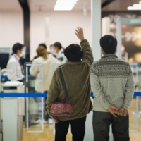A woman waves goodbye to a departing passenger at Narita airport in Chiba Prefecture on Tuesday. European Union governments plan to remove Japan from their list of countries whose residents should be allowed to visit the bloc during this phase of the coronavirus pandemic, according to an EU official. | BLOOMBERG