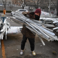 A worker collects used building material for recycling in Beijing. | AFP-JIJI