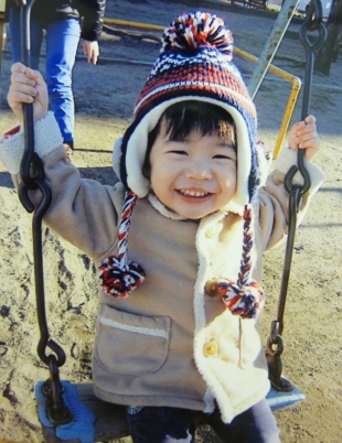 Kosuke, who died after malpractice at Tokyo Women's Medical University Hospital at age 2 in February 2014 and whose family name is being withheld, smiles on a swing in December 2013. | COURTESY OF KOSUKE'S FAMILY / VIA KYODO