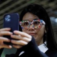An employee of online fashion retailer Zozo Inc. demonstrates the smartphone application for \"Zozoglass,\" used to measure skin tone for ordering cosmetics online, at the company\'s office in Tokyo on Thursday. | REUTERS