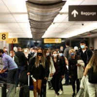 Travelers wearing protective face masks to prevent the spread of the coronavirus reclaim their luggage at the airport in Denver in November. | REUTERS