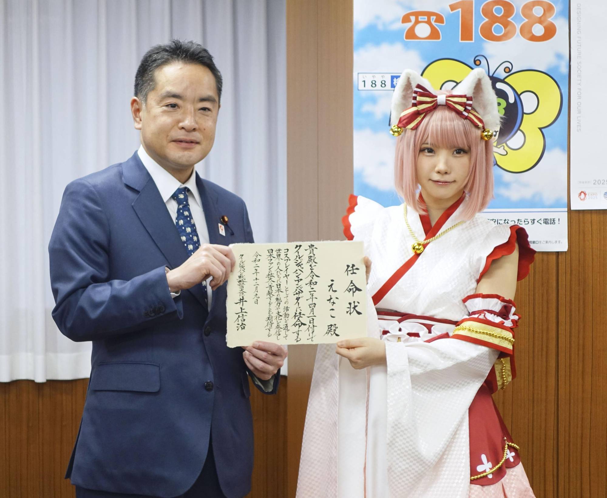 Shinji Inoue, minister in charge of Cool Japan strategy, hands a letter to cosplayer Enako that names her as Cool Japan ambassador, in Tokyo in December. | KYODO
