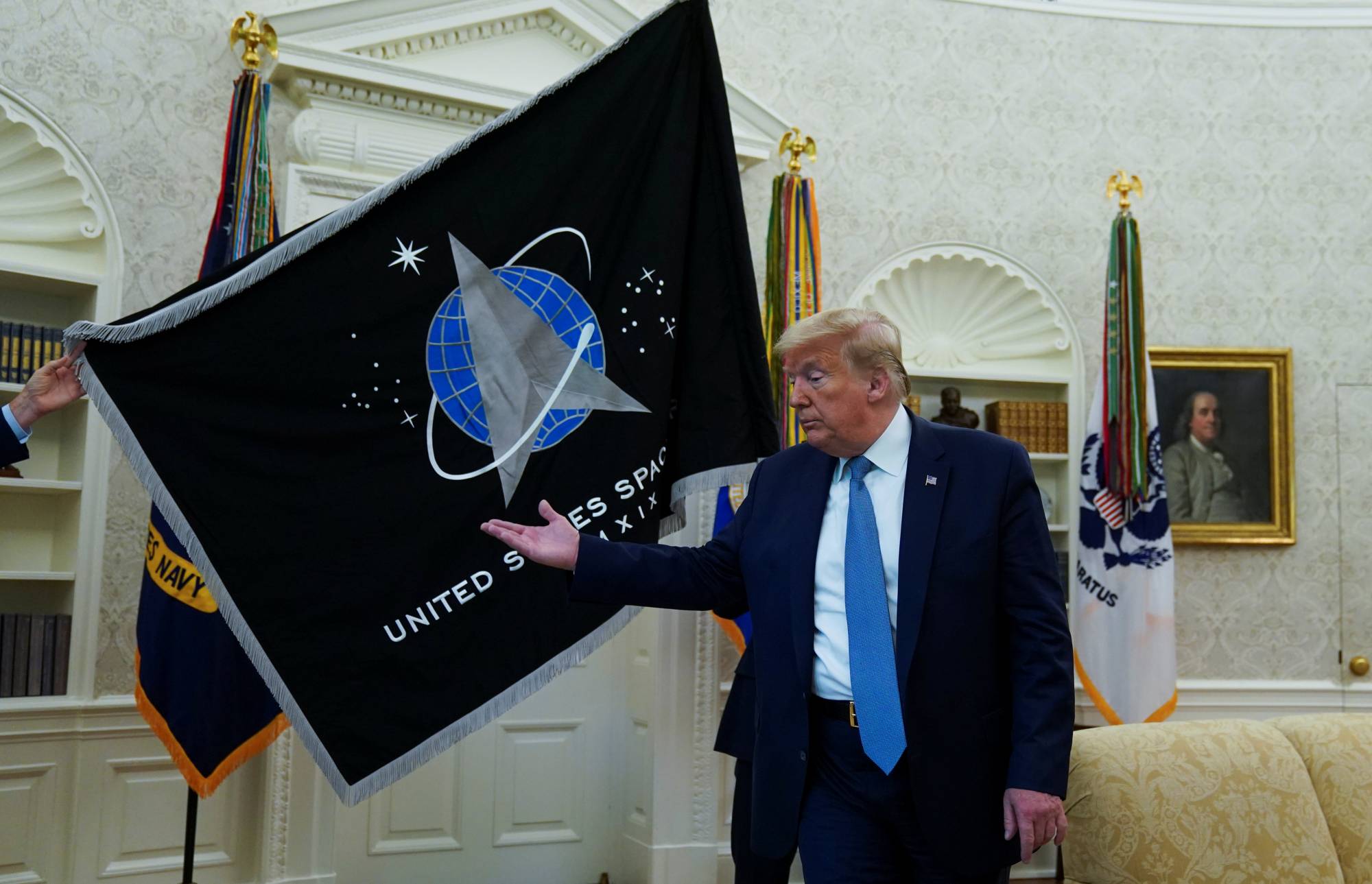 Former U.S. President Donald Trump inspects the U.S. Space Force flag during a presentation of the banner in the Oval Office in Washington in May. |  REUTERS