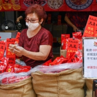 A vendor sells nuts from a shop next to a sign telling the public to prevent the spread of the coronavirus, in Chinatown, Singapore, on Jan. 5. | AFP-JIJI