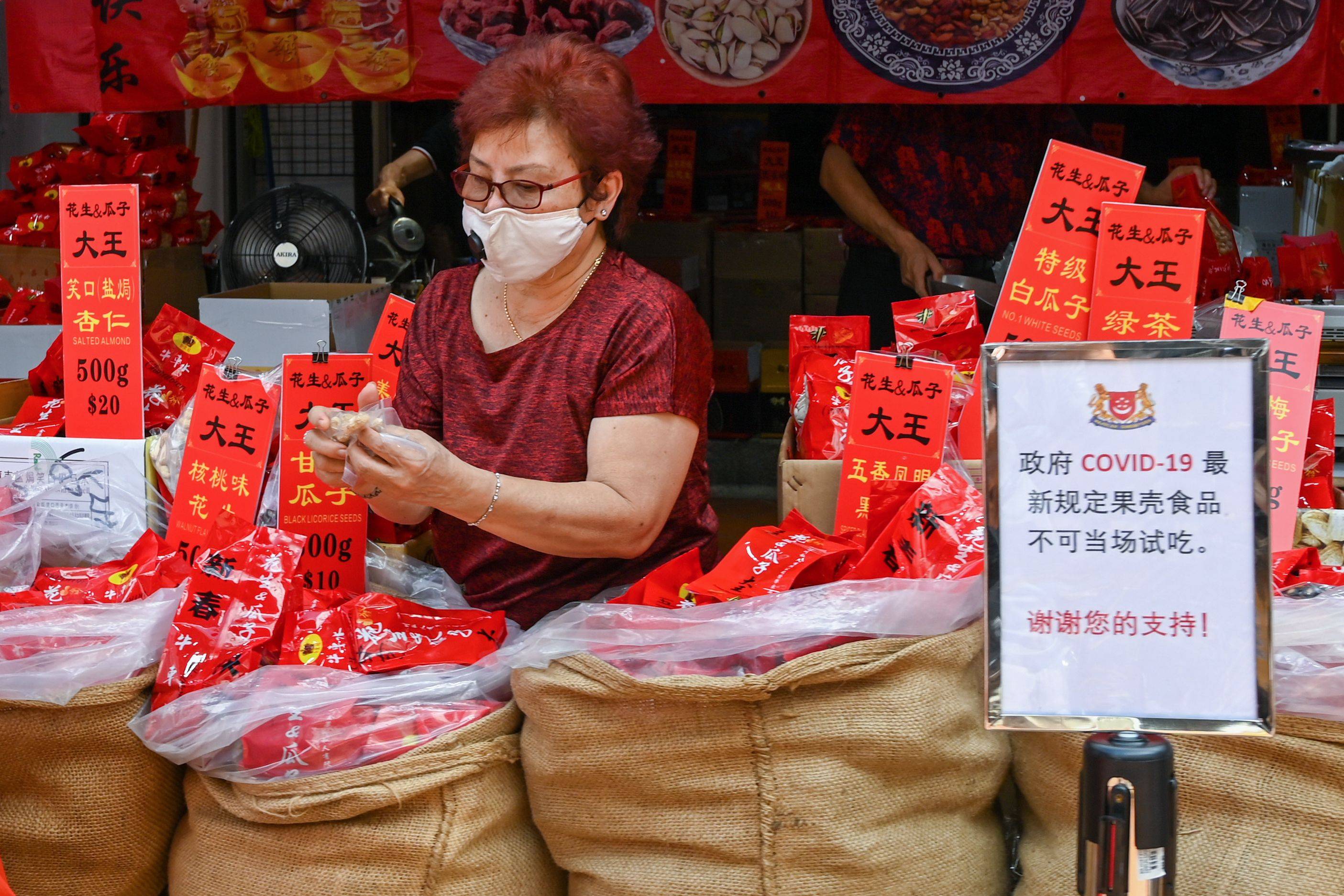 A vendor sells nuts from a shop next to a sign telling the public to prevent the spread of the coronavirus, in Chinatown, Singapore, on Jan. 5. | AFP-JIJI