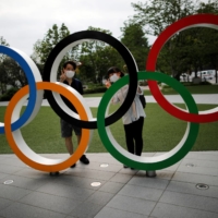 Visitors wearing face masks pose for photos with the Olympic rings outside the Japan Olympics Museum on July 22. | REUTERS