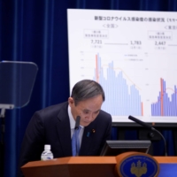 Prime Minister Yoshihide Suga bows during a news conference in Tokyo on Tuesday as he announces the government has approved a monthlong extension of its coronavirus state of emergency, less than six months before the pandemic-postponed Olympic Games open. | POOL / VIA AFP-JIJI