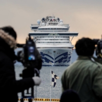 Reporters film the Diamond Princess cruise ship as it approaches the port of Yokohama on Feb. 6, 2020. | REUTERS