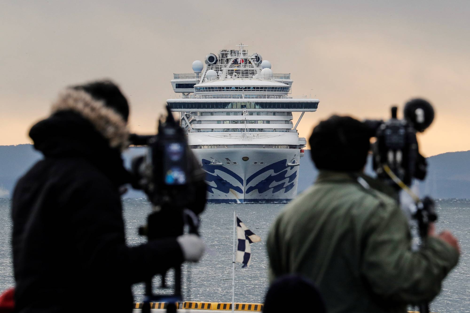 Reporters film the Diamond Princess cruise ship as it approaches the port of Yokohama on Feb. 6, 2020. | REUTERS