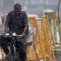 A commuter rides past during heavy rains in Chennai on Jan. 6.  | AFP-JIJI