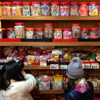 Pick n’ mix: Children browse the colorful, packed shelves of a traditional <em>dagashiya</em> (old-fashioned sweets shop). | REBECCA SAUNDERS
