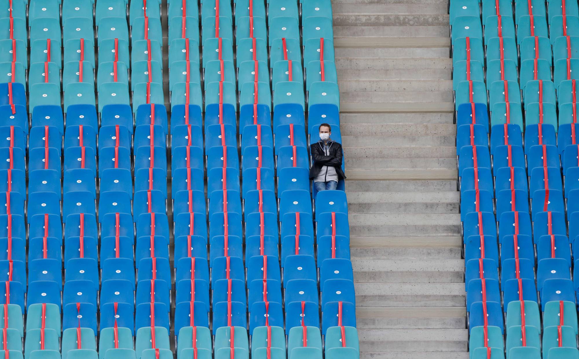 Red ribbons are placed on seats to maintain social distancing as a man sits alone ahead of a soccer match in Leipzig, Germany, in October.  | AFP-JIJI