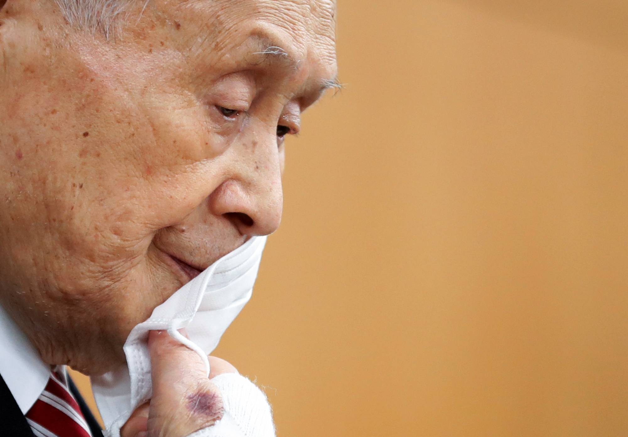 Tokyo 2020 Olympics chief Yoshiro Mori takes off his face mask during a news conference in Tokyo on Thursday. | POOL / VIA REUTERS