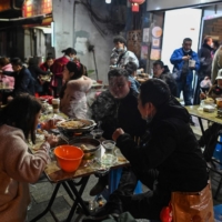 People eat in front of a restaurant in Wuhan, China, on Friday.  | AFP-JIJI