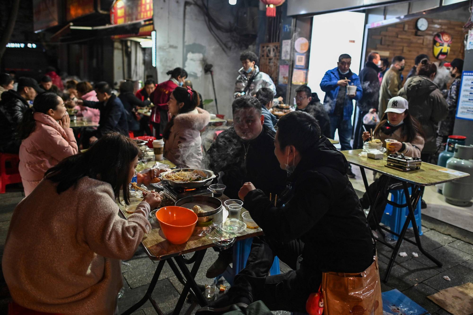 People eat in front of a restaurant in Wuhan, China, on Friday. | AFP-JIJI