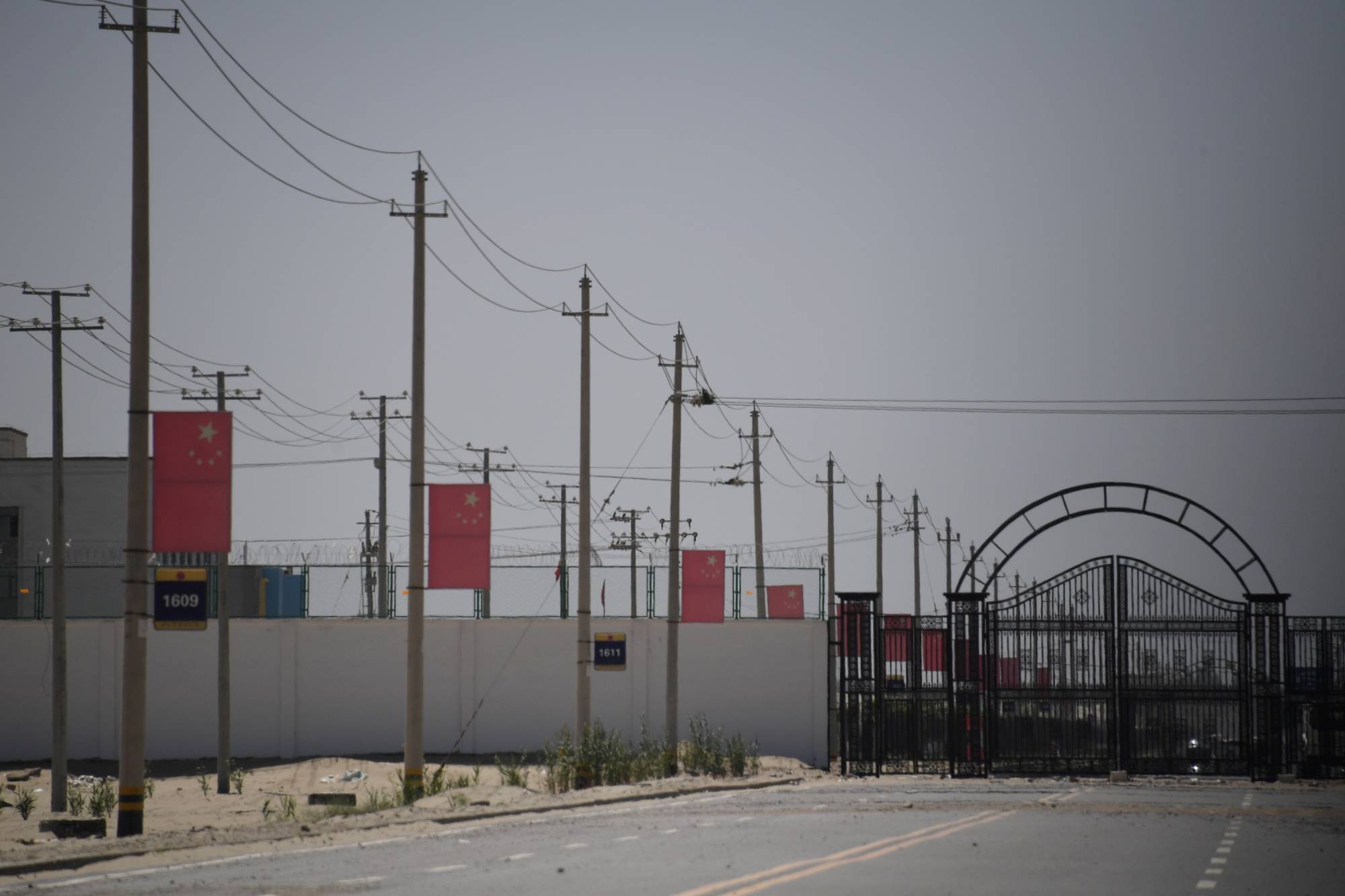 Chinese flags line a road leading to a facility believed to be a re-education camp where mostly Muslim ethnic Uighur are detained, on the outskirts of Hotan in China's northwestern Xinjiang region in May 2019. | AFP-JIJI