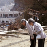 Emperor Akihito and Empress Michiko bow in April 2011 during their visit to Minamisanriku, Miyagi Prefecture, following the tsunami the month before. | KYODO