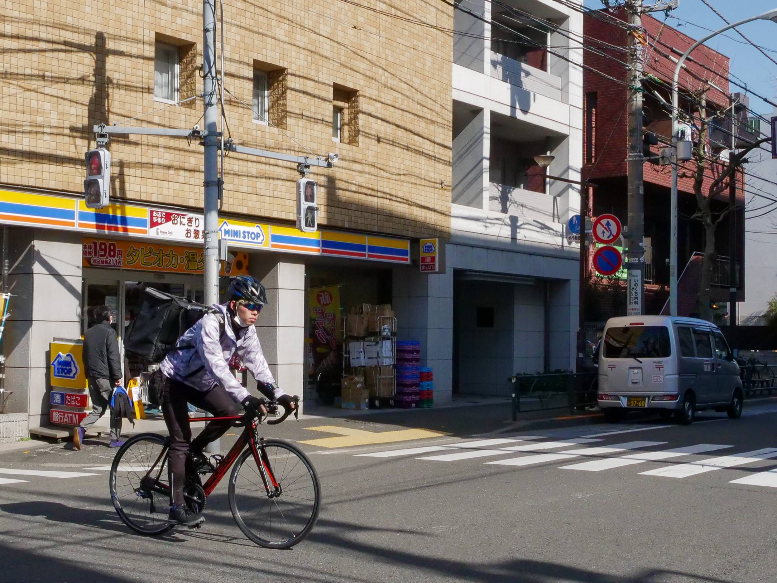 On the go: A helmeted cyclist passes in front of a convenience store in the Tokyo metropolitan area. | PHOEBE AMOROSO