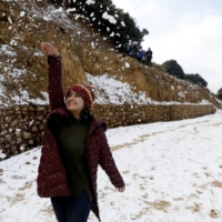 A woman plays with snow in Kathmandu in 2019. Climate researchers warn that snowy winters will become rarer in Nepal over the coming decades. | REUTERS
