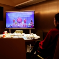 People watch the Lunar New Year gala after having dinner at a hot pot restaurant in Beijing on Thursday. | REUTERS