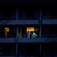 A medical worker stands on the balcony of a hotel where members of the World Health Organization team tasked with investigating the origins of COVID-19 were staying in Wuhan, China, on Feb. 3. | REUTERS