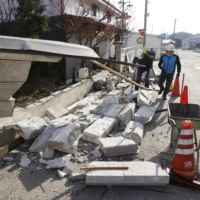 A toppled concrete wall is seen in the town of Kunimi, Fukushima Prefecture on Sunday morning, after a powerful earthquake hit the Tohoku region late Saturday. | KYODO