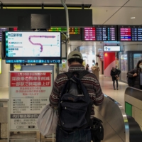 Screens alert passengers of the suspension of operations of shinkansen services in the Tohoku region at Tokyo Station on Sunday. | AFP-JIJI
