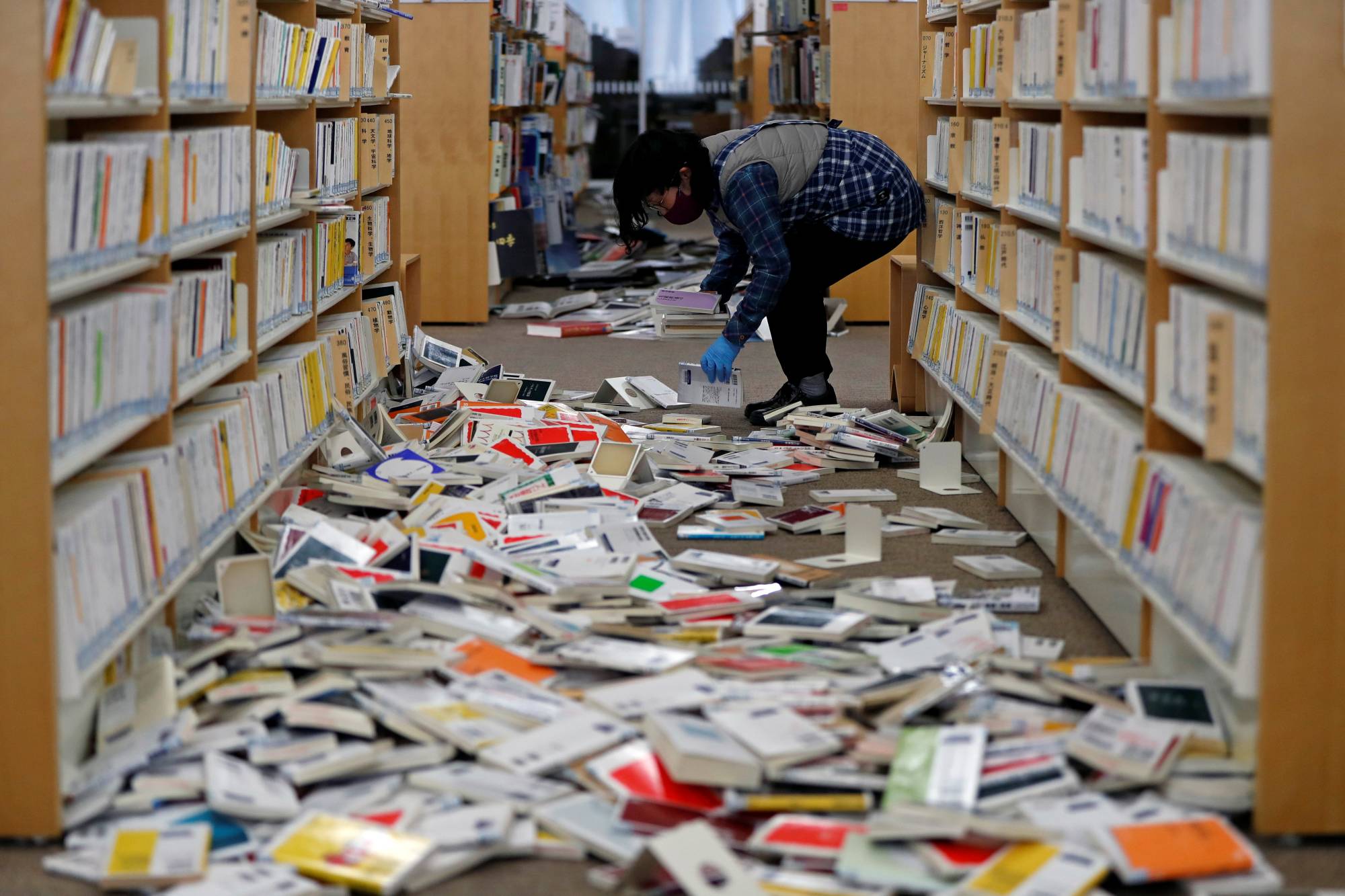 A staff member picks up books at Iwaki City library in Fukushima Prefecture. | REUTERS