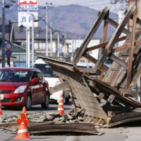 A toppled house gate blocks the road in Koori, Fukushima Prefecture, on Sunday. | KYODO