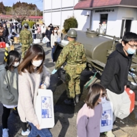 People receive water from the Self-Defense Forces in Shinchi, Fukushima Prefecture, on Sunday after the town suffered severe supply cuts following a strong quake the previous day. | KYODO