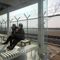 An elderly couple drink coffee next to a barbed wire fence at the Imjingak tourist park beside the civilian buffer zone that leads to the Demilitarized Zone separating the two Koreas, in Paju, north of Seoul, on Friday. | AFP-JIJI