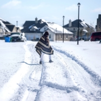 A man walks to his friend\'s home in a neighborhood without electricity as snow covers Pflugerville, Texas, on Monday.  | AUSTIN AMERICAN-STATESMAN / USA TODAY NETWORK / VIA REUTERS