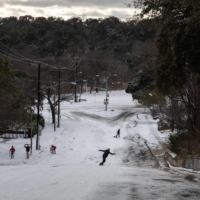A man snowboards down a road in Austin, Texas, on Monday.  | TAMIR KALIFA / THE NEW YORK TIMES